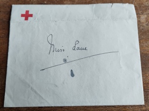 White envelope with a red cross in the top left hand corner and "Miss Lane" handwritten across it.