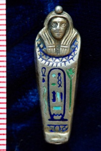 Miniature silver locket in the shape of an Egyptian mummy casket, inlaid with blue and green enamel hieroglyphics. 