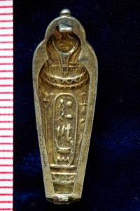 Inside of miniature silver Egyptian mummy casket charm, showing hieroglyphics in relief.
