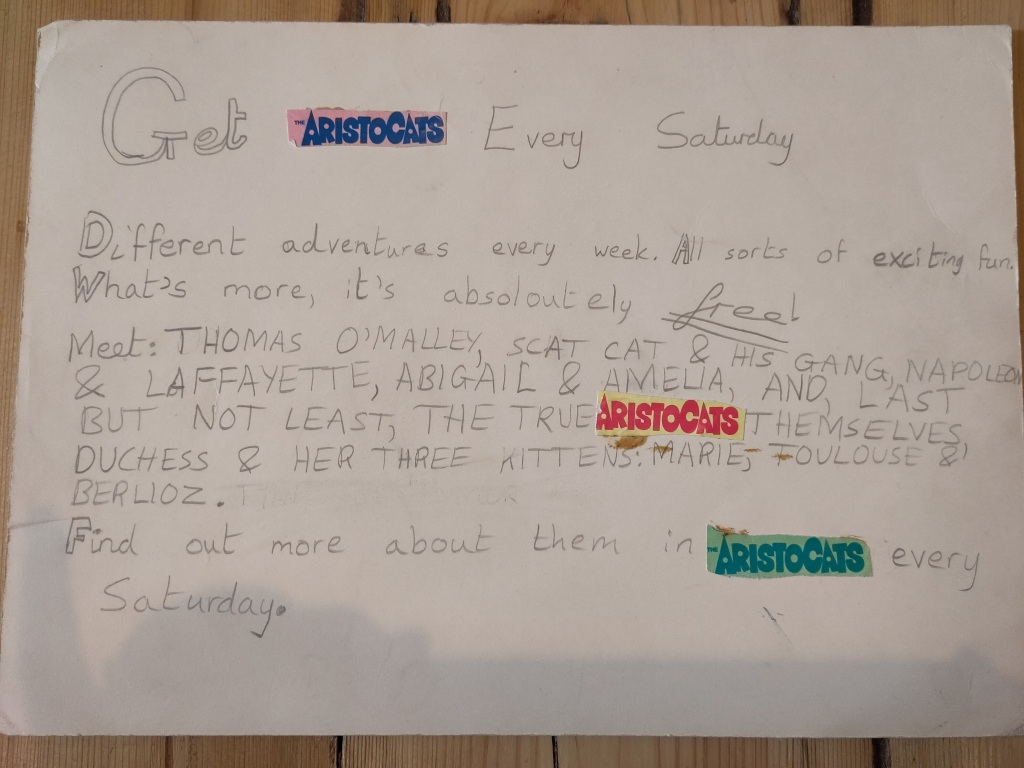 A sign written in a child's handwriting, advertising The Aristocats comic every Saturday.