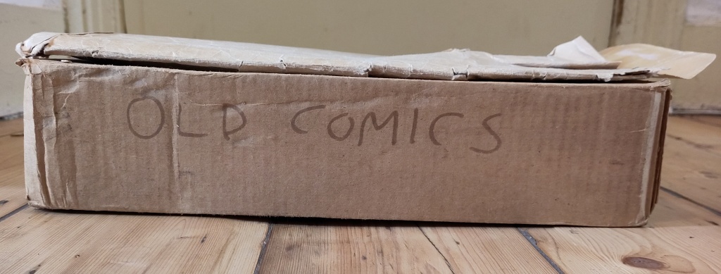 A dusty cardboard box with "Old Comics" written on the side. 